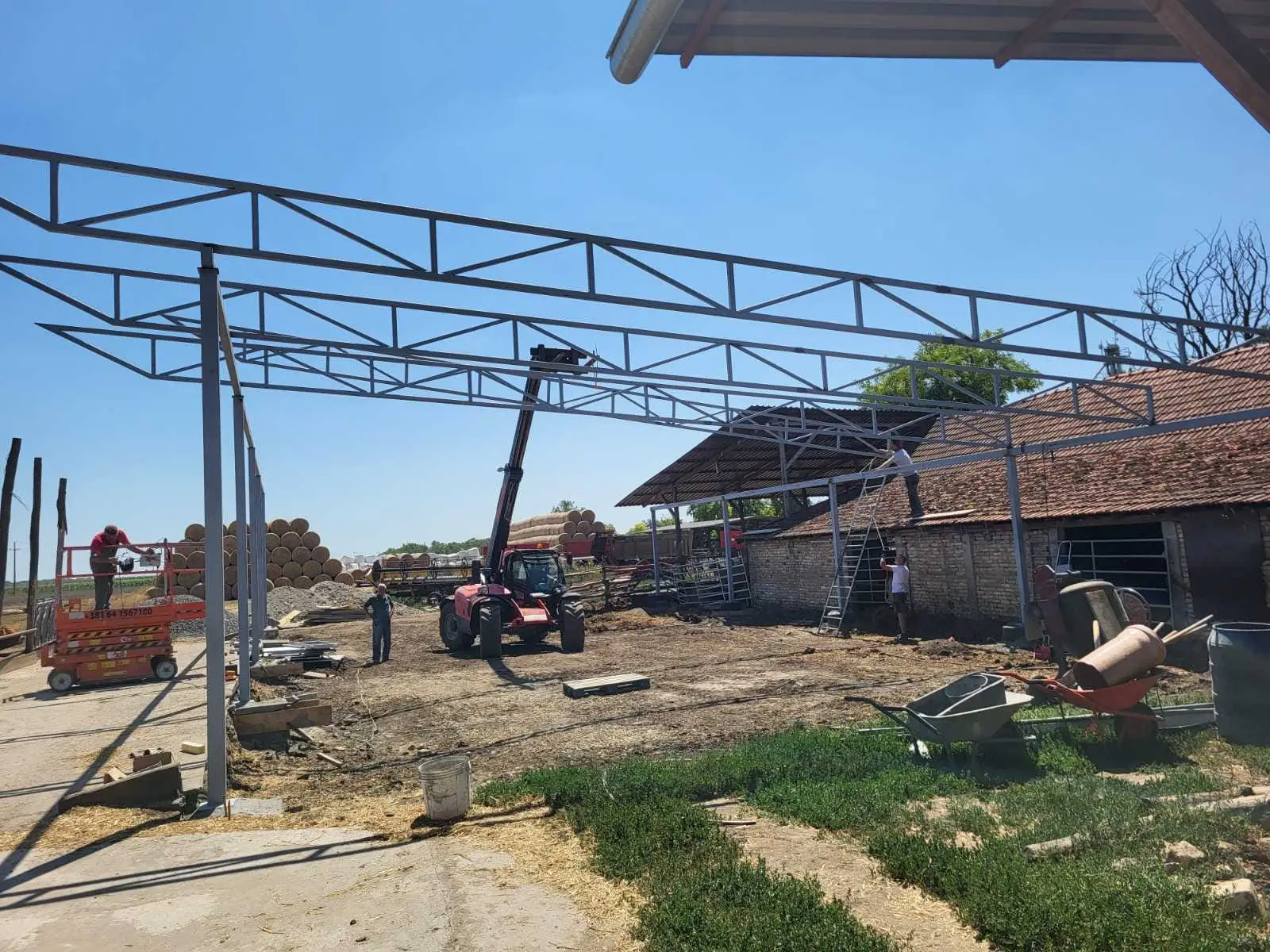 Steel truss canopy structure being installed above a farm building