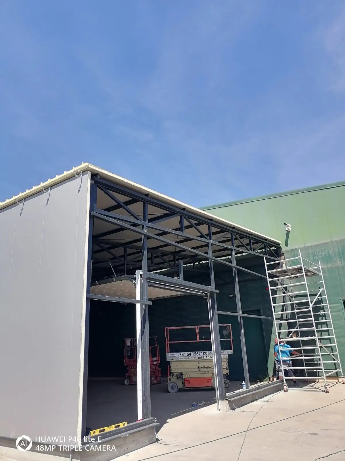 Steel-frame warehouse extension under construction next to an existing building