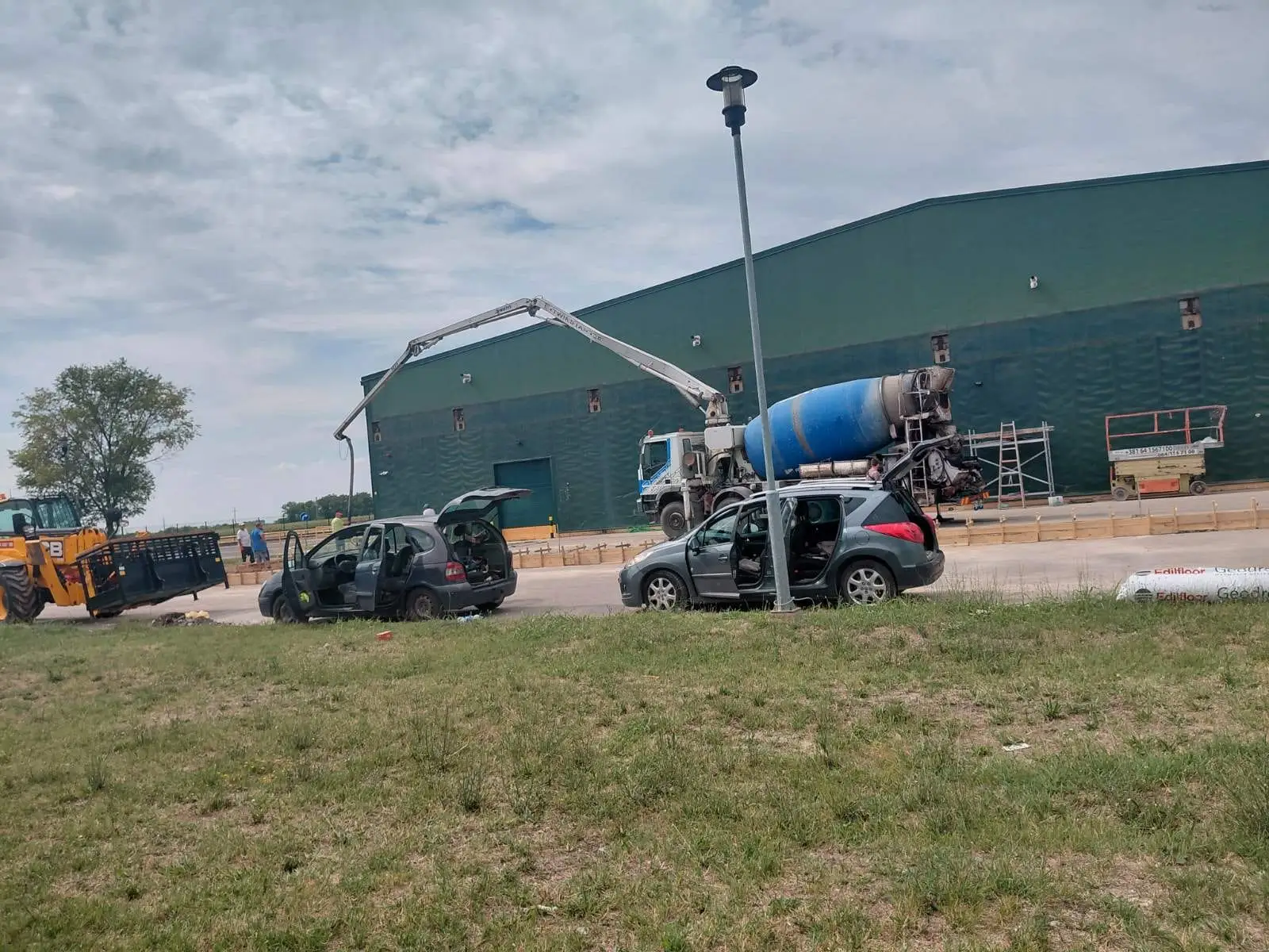 Concrete pump truck pouring foundations at a steel-frame warehouse site