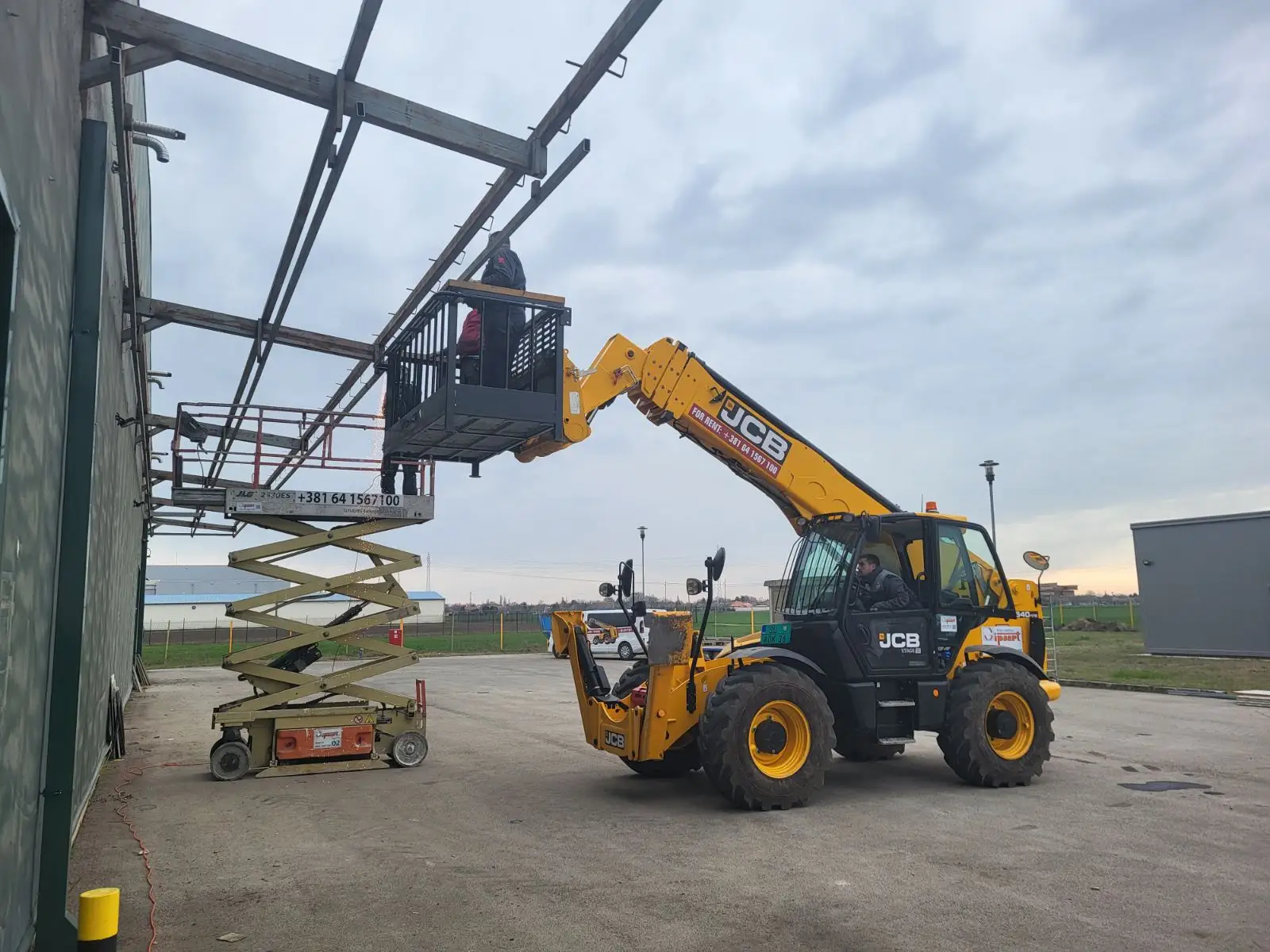 Telehandler and scissor lift assembling a steel building frame