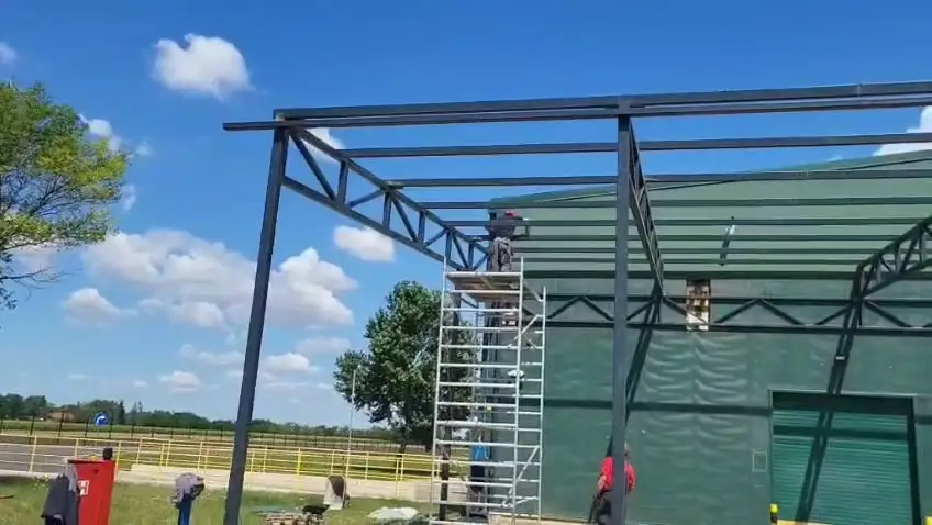 Steel frame under construction with workers on a scaffold tower